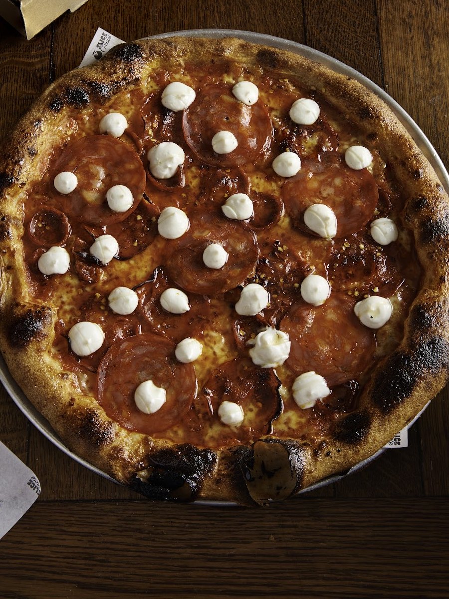 A pizza on a metal tray on a dark wooden table