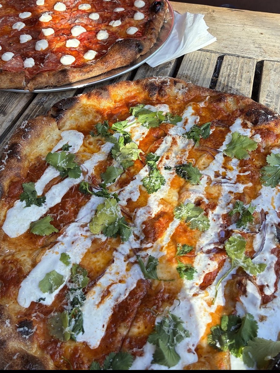 Two Slice Circle pizzas on trays on a wooden table